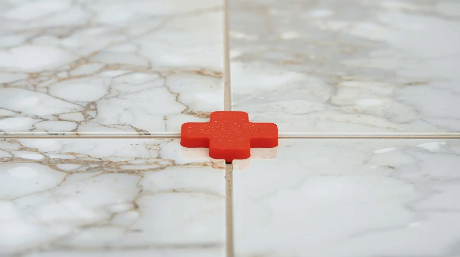 Plastic spacers creating a mandatory grout joint between ceramic tiles to prevent cracking.